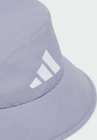 Jasnofioletowa czapka typu bucket wykonana z miękkiego materiału, z białym logo w trzy paski po boku i zaokrąglonym, szerokim rondem.