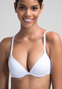 Sujetador push-up blanco con tejido suave, copas triangulares, tirantes ajustables y hardware mínimo. Sin patrones visibles ni adornos.