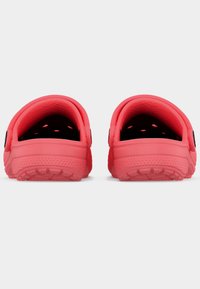 Paire de sabots rouges à enfiler avec des trous d'aération et des semelles texturées, vue de dos sur fond blanc.