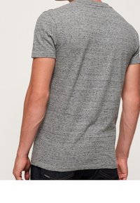 Grå kortärmad t-shirt i strukturerad tygkvalitet, med rundad halsringning. Synlig bakdesign med åtsittande passform.