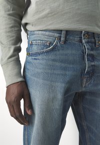 Ljusblå jeans i denim med en klassisk femfickorsdesign, kopparnitar och subtila slitningar framtill.