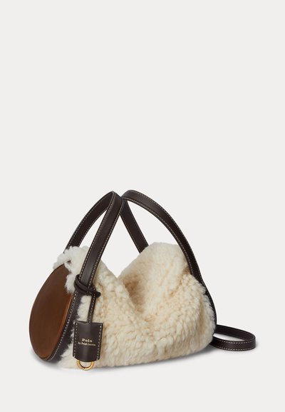 Ruskea nahkainen käsilaukku, jossa on kermahtava karvainen vuori. Varustettu kahdella kaarevalla kahvalla, nimilapulla ja nahkakoristeiden sileällä viimeistelyllä.