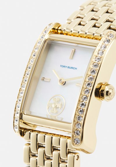 Goudkleurig Tory Burch polshorloge met rechthoekige wijzerplaat, met kristallen bezette lunette, minimalistische wijzerplaat en metalen schakelen armband.
