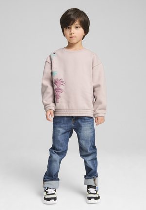 Ljusrosa sweatshirt med grafiskt tryck, rund halsringning och ribbade ärmmuddar; ihopparad med denimjeans och svarta sneakers med vita accenter.