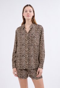 Setti med leopardmønster i sovetøy bestående av en knapp-opp skjorte med lange ermer og matchende shorts. Laget av mykt stoff med en glatt tekstur.