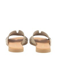 Sandalias planas beige con la parte trasera abierta y diseño recortado. Fabricadas con material suave, cuentan con una plantilla texturizada y una suela lisa.