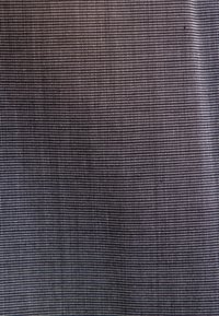 Gros plan d'un tissu gris foncé avec un motif en grille fine de petits points blancs uniformément espacés.