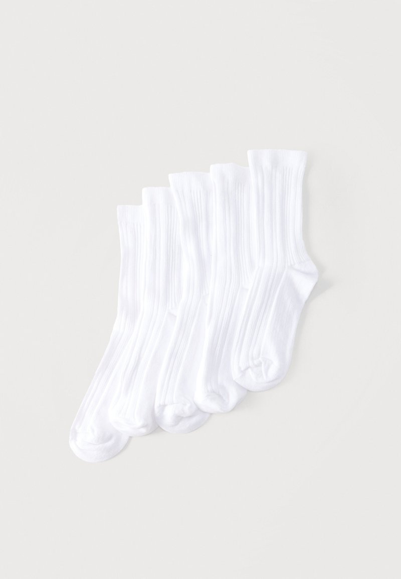 Cinq paires de chaussettes blanches côtelées montantes disposées côte à côte sur un fond clair.