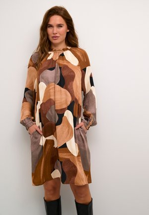 Brown and cream patterned dress with long sleeves, gathered neckline, and side pockets. Smooth fabric with a relaxed, loose fit.