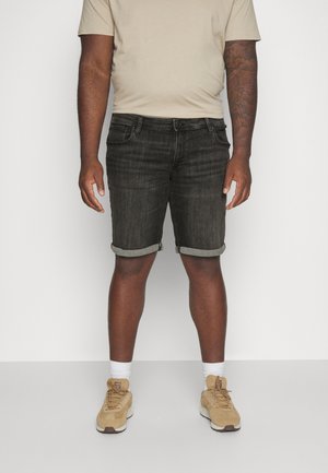 Czarne szorty z denimu z podwiniętymi mankietami, posiadające pięć kieszeni i klasyczny krój. Połączone z beżowym t-shirtem i brązowymi sneakersami.