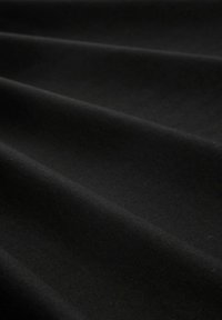 Schwarzer Baumwollstoff mit glatter Textur, der sanfte, subtile Falten aufweist und eine wellenartige Erscheinung erzeugt. Keine sichtbaren Muster oder Akzente.