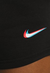 Svarta träningsshorts i tyg med en liten Nike-logotyp i rött, ljusblått och vitt, placerad nära nederkanten, med en slät textur.