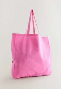 Sac tote en toile rose avec deux anses robustes, grande forme rectangulaire et texture douce. Aucun motif ni élément métallique visible.