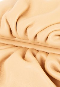 Matière en cuir beige doux avec une texture fine visible et des plis et rides naturels.