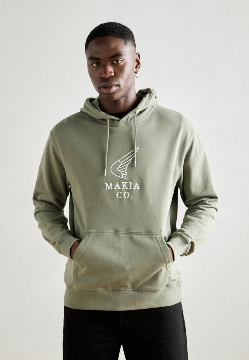 Haut à capuche vert olive en coton, présentant une poche avant et un logo avec des ailes. Coupe décontractée avec cordon de serrage ajustable au niveau de la capuche.