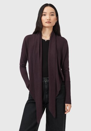 Long cardigan à l'avant ouvert en tissu tricoté violet foncé. Présente une coupe décontractée et des poignets côtelés. Porté sur un haut noir et un jean taille haute.