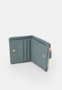 Portafoglio in pelle blu testurizzata con hardware dorato, dotato di scomparti per carte, una tasca con zip e chiusura a scatto. Design compatto.