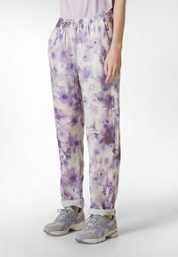 Lichte, met bloemenpatroon versierde broek in lavendel en crème, met een elastische tailleband, een losse pasvorm en opgerolde pijpen. Gecombineerd met een paar grijze sneakers.