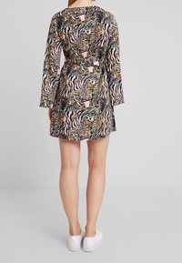 Sukienka z krótkim rękawem z czarno-białym złotym abstrakcyjnym nadrukiem zwierzęcym, z talią ściągniętą i prostym dołem, wykonana z lekkiego materiału.
