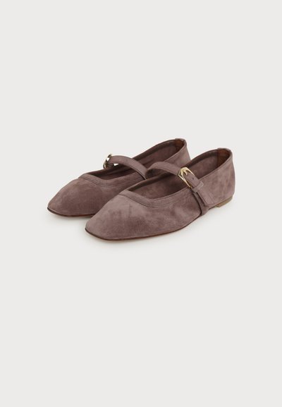 Paire de ballerines Mary Jane en daim mauve à bouts pointus, petits talons et fines brides fermées par de petites boucles dorées, sur fond blanc.