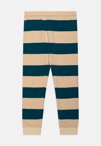 Leggings a rayas en beige y azul oscuro, con una cinturilla elástica, piernas ajustadas y una textura de tela suave y ligera.