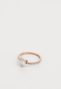Rose gold -sormus, jossa on sydämen muotoinen kirkas kivi, ja joka on koristeltu pienillä kirkkailla kristalleilla yhdellä puolella.