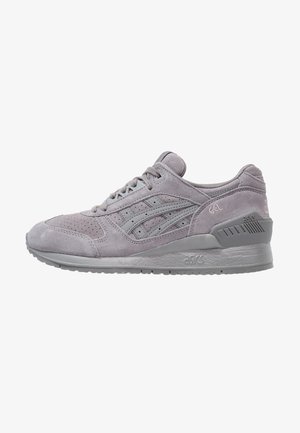 Baskets ASICS en daim gris clair avec lacets, bout perforé et semelle texturée, vues de côté sur fond blanc.