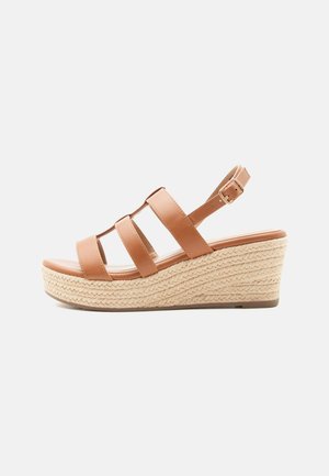 Sandale compensée en cuir marron avec trois brides et une boucle à la cheville, dotée d'une semelle plateforme espadrille tressée.
