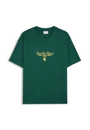 T-shirt vert foncé à manches courtes et col rond avec texte jaune "Away From Keyboard, Find Me Outside in the Real World" avec un petit graphisme de lion.