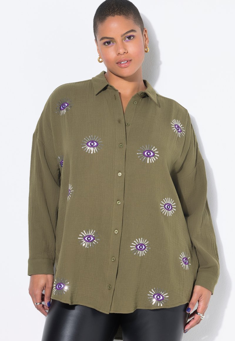Chemise vert olive à boutons avec une grande broderie représentant un œil violet et un motif de rayons de soleil, coupe décontractée, manches longues, tissu texturé et subtile brillance.