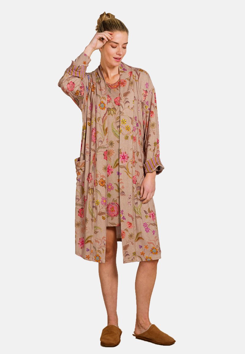 Beige kimono-stijl jas met bloemenpatroon en zakken. Beschikt over lange mouwen met gestreepte manchetten. Gemaakt van lichte stof.