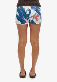 Pantalones cortos con estampado floral de hojas azules y acentos rosas sobre un fondo blanco. Presenta dos bolsillos traseros y un diseño ajustado.