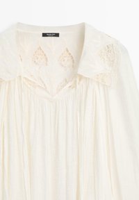 Blusa color crema con colletto rifinito in pizzo e tessuto arricciato sotto lo scollo, marca Massimo Dutti.