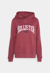 Sudadera con capucha en color burdeos, con un bolsillo tipo canguro, que presenta un gráfico en blanco y azul marino que dice "Los Angeles HOLLISTER". Tejido suave con puños acanalados.