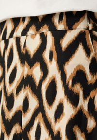 Rock aus Leopardenmusterstoff mit einer Farbpalette aus Beige, Braun und Schwarz. Verfügt über eine glatte Textur und ein gerades Taillenbanddesign.