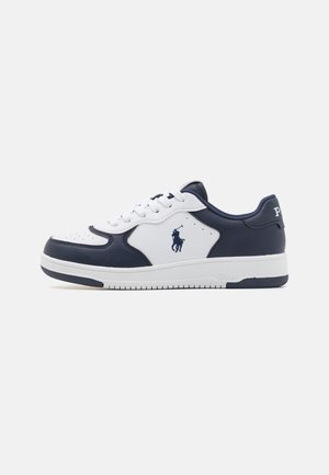 Zapatilla de cuero blanca y navy con puntera perforada, costuras elevadas, logo lateral, cordones planos, suela acolchada y detalles texturizados.