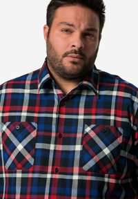Camicia in cotone a quadri con motivi checkered rosso, blu e nero, due tasche sul petto e colletto classico. Tessuto morbido, vestibilità regolare.