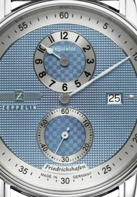 Regulator horloge met een blauwe gestructureerde wijzerplaat, zilverkleurige hardware, drie subdials en een datumaanduiding op 6 uur. Gefabriceerd in Duitsland.