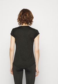 Mörkgrå tight t-shirt med korta ärmar, rundad nederkant och lätt, slät textur. Styad med svarta leggings.