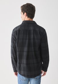Zwart-grijze geruite flanellen shirt, lange mouwen, met knoopmanchetten en puntige kraag. Zachte textuur met een ontspannen pasvorm en afgeronde zoom.