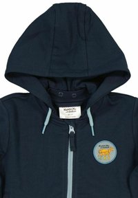 Tummansininen huppari, jossa on etuvetoketju ja vaaleansiniset nyörit. Hupparissa on pyöreä logo-ompelu, jossa on kuva hevosesta. Pehmeää puuvillamateriaalia.