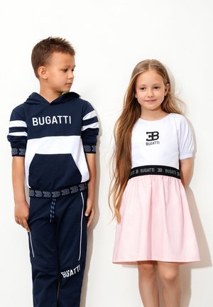 Marineblau-weißer gestreifter Kapuzenpullover mit "BUGATTI"-Logo, kombiniert mit passenden Hosen. Mädchen in weißem Oberteil und rosa Rock mit schwarzem Taillenbund, ebenfalls mit "BUGATTI"-Logo.