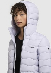 Padded white hooded jacket with a black zip and logo. Textured, quilted design with an adjustable hood and high collar for warmth.