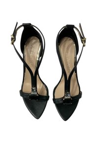 Scarpe nere con tacco alto e punta appuntita, dotate di una cinghia alla caviglia e di un accento decorativo in pietra nera sul davanti. Texture liscia.