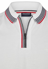 Polo shirt blanc avec un col zippé arborant des rayures noires, rouges et blanches. Le matériau a une finition texturée. Étiquette de marque : HECHTER PARIS.