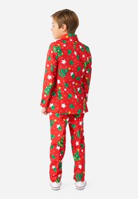 Completo natalizio rosso con alberi di Natale verdi e stelle bianche. Design su misura con pantaloni abbinati e scarpe da ginnastica bianche in contrasto.