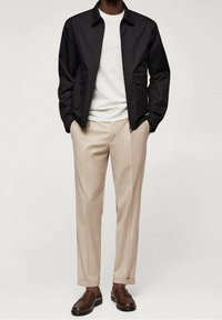 Czarna lekka kurtka, biała koszulka z okrągłym dekoltem, beżowe spodnie i brązowe mokasyny. Kurtka posiada dwie boczne kieszenie, dopasowany krój.