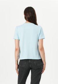 Lyseblå kortermet t-skjorte laget av mykt stoff med rund hals, med en avslappet passform og rett nederkant. Uformell design.