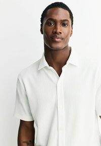 Weißes Hemd mit kurzen Ärmeln, vertikalen Streifen, Kragen und durchgehender Knopfleiste. Glatte Textur mit lockerem Sitz.