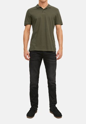 Olivgrünes Polohemd mit Kragen, kombiniert mit dunklen Jeans und schwarzen Schuhen. Schlichtes Design, kurze Ärmel und lässige Passform.